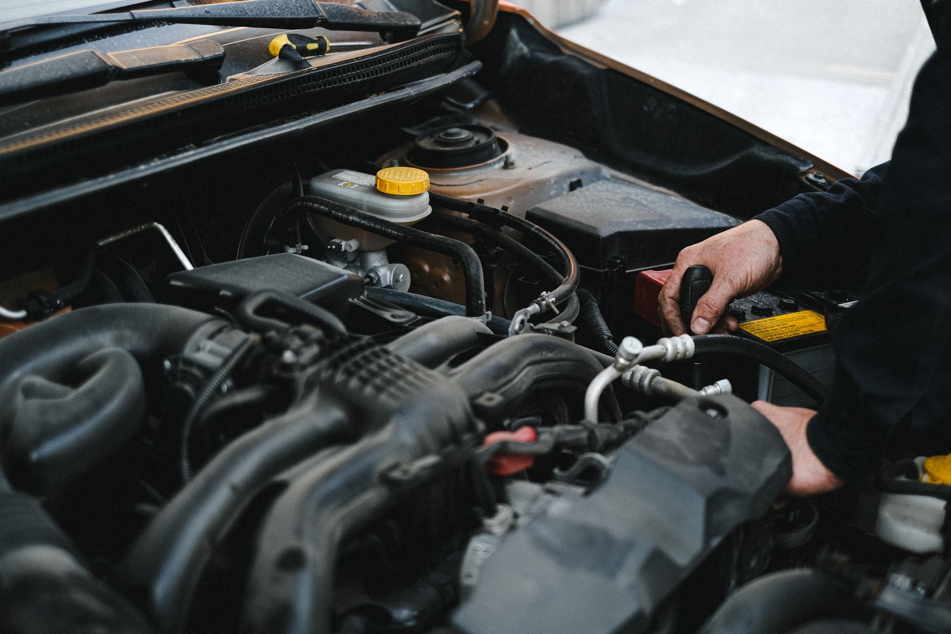 Mechanic working on engine of older car during retrofit or repair work related to clean air zone compliance